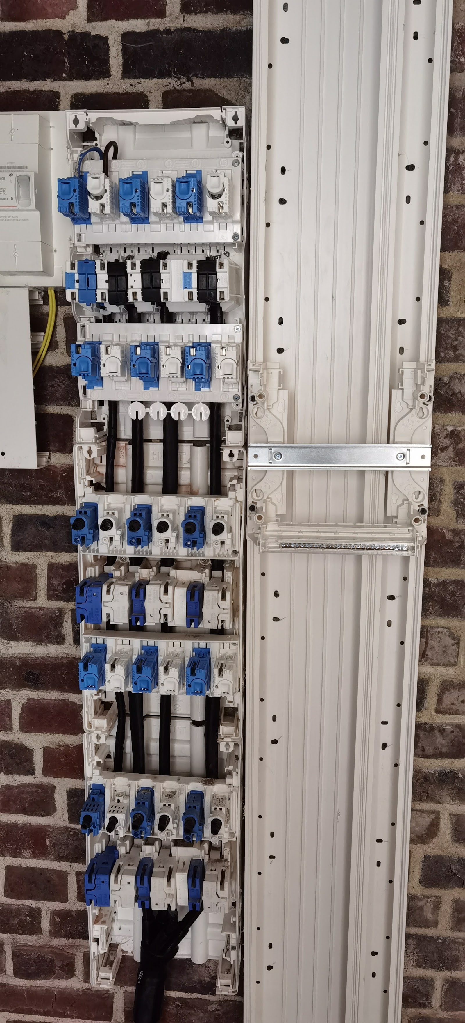 Câblage d'un tableau électrique en cours d'installation sur mur de briques